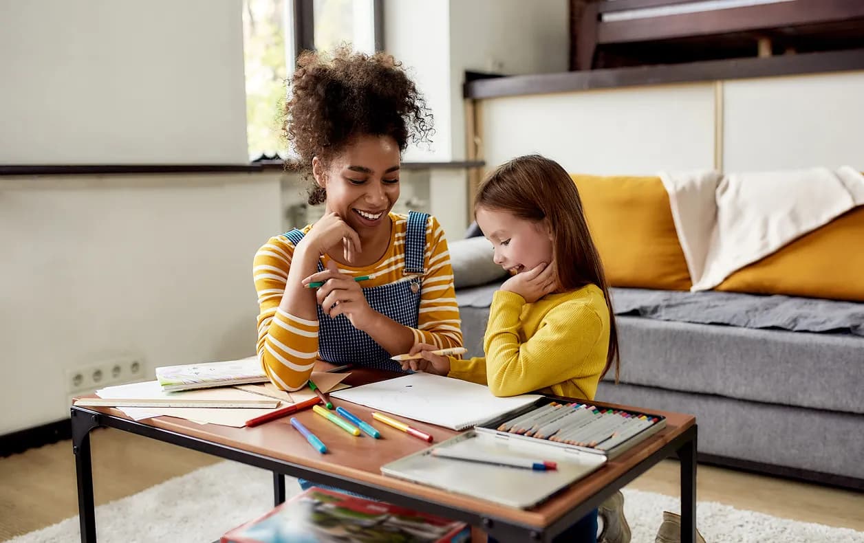 Caregiver helping two children with homework on a couch