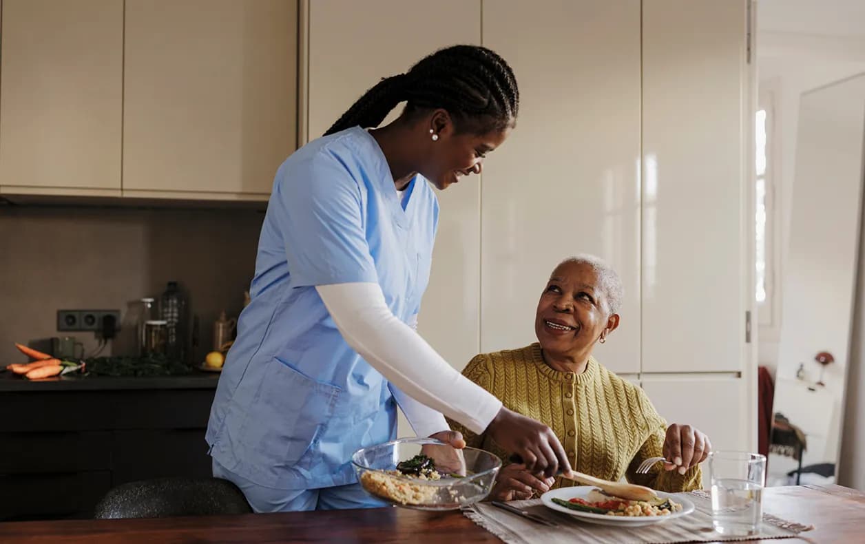 Home health aide talking with an older adult in a kitchen